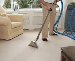 Carpet cleaning professional removing dirt and stains with a hot-water extraction tool in a home, Fargo, ND.